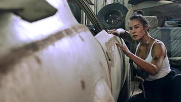 aantrekkelijk jong vrouw mechanisch arbeider repareren een wijnoogst auto in oud garage. foto