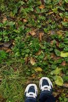 vrouw voeten in blauw sport schoenen Aan grond met gras foto