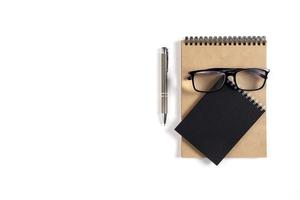 twee blocnotes, pen en bril liggen Aan een wit oppervlakte foto