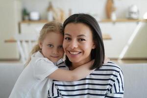 portret van mam en schattig weinig meisje. blond kind knuffels mama. knap vrouw en meisje samen Bij huis. foto