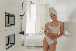 jong slank vrouwelijk model poseren in moderne lichtgekleurde badkamer foto