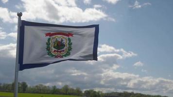 west Virginia vlag Aan een vlaggenmast golvend in de wind, blauw lucht achtergrond. 3d illustratie foto