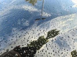 regendruppels op een zwart metalen auto-oppervlak in een close-upweergave. foto