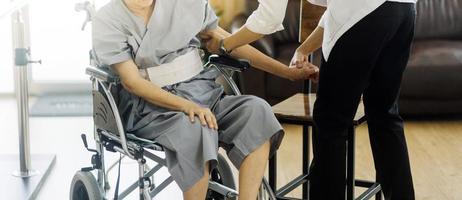 dokter of verpleegster verzorger met senior Mens in een rolstoel vervelend beschermend maskers Bij huis of verpleging huis foto