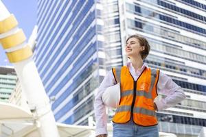 Kaukasisch vrouw ingenieur is op zoek over- de hoogbouw gebouw terwijl inspecteren de bouw project voor modern architectuur en echt landgoed ontwikkeling concept foto