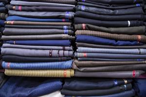 gevormde textiel stoffen gestapeld Aan een kleinhandel winkel plank voor uitverkoop foto