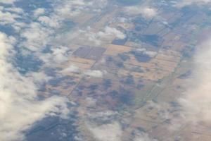 luchtfoto van landbouwgrond. uitzicht vanuit het vliegtuig naar de grond. vierkanten van velden onder de wolken foto