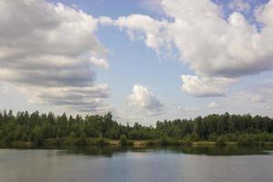 zomerlandschap met een prachtig meer met dennenbomen en beboste bergen tegen een bewolkte hemel foto