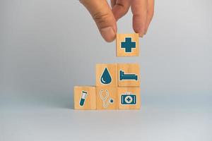 hand- Holding houten kubussen blok met verzekering Gezondheid auto medisch symbool Aan achtergrond en kopiëren ruimte. foto