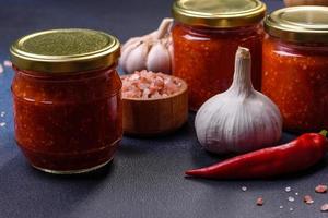 eigengemaakt heet tomaat saus adjika in potten. tomaten, chili peper, knoflook en kruiden foto