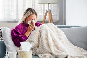 ziek dag Bij huis. blond vrouw heeft vloeibaar en gemeenschappelijk koud. hoesten. detailopname van mooi jong vrouw gevangen verkoudheid of griep ziekte. portret van ongezond meisje gevoel pijn in keel. foto