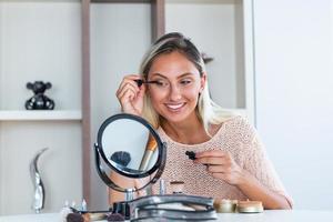 vrouw toepassen zwart mascara Aan wimpers met bedenken borstel. schoonheid verzinnen. portret van mooi jong vrouw toepassen zwart mascara Aan wimpers, Holding borstel in hand. foto