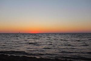 gouden zonsondergang of zonsopgang in de diepe donkere oceaan. luchtfoto van zonsondergang en tot aan de zee. gele en oranje kleurrijke lucht. romantische mooie hemel in het voorjaar. foto