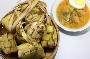 ketupat is traditioneel Indonesisch voedsel, geweven kokosnoot bladeren gevulde met rijst- en gegeten met papaja groenten, , geserveerd Aan eid al-fitr of eid al-adha foto