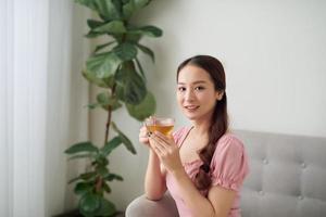 mooi jong Aziatisch vrouw drinken thee in de ochtend- Bij leven kamer. foto