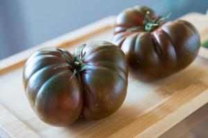 twee heerlijk vers tomaten Aan een houten snijdend bord foto