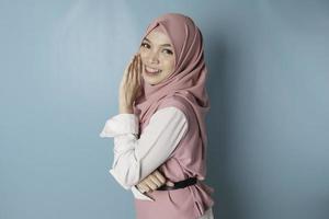 jong Aziatisch moslim vrouw vervelend roze hijaab, hand- Aan mond vertellen geheim gerucht, fluisteren kwaadaardig praten gesprek foto