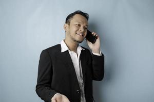 portret van een Aziatisch zakenman vervelend een zwart pak glimlachen terwijl pratend Aan de telefoon foto