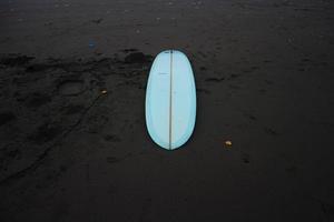 surfen bord in de zand Bij de strand. met zonsondergang licht foto