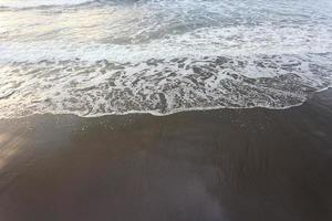zachte golf van blauwe oceaan op zandstrand. achtergrond. foto