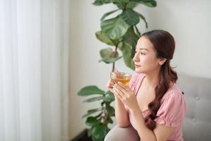 mooi jong Aziatisch vrouw drinken thee in de ochtend- Bij leven kamer. foto