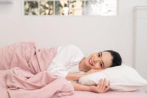 ontwaken van slaap gelukkig vrouw in bed en zacht hoofdkussen deken foto