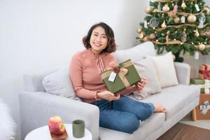 de meisje met cadeaus in de buurt de Kerstmis boom foto