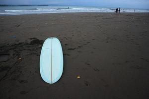 surfen bord in de zand Bij de strand. met zonsondergang licht foto