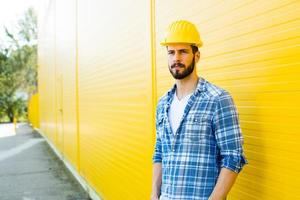 volwassen werknemer met helm op gele muur foto