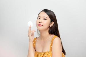 foto van een mooi jong mooi Aziatisch vrouw met gezond huid poseren naakt geïsoleerd over- wit muur achtergrond Holding katoen kussentjes.