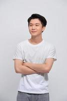 portret van jong Aziatisch Mens geïsoleerd Aan wit achtergrond, staand met gekruiste armen, glimlachen en op zoek Rechtdoor Bij camera foto