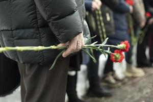 twee anjers in man's hand. details van begrafenis ceremonie. herdenkings- bloemen in hand. foto