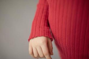 kind hand- in rood trui. details van baby's kleren. foto