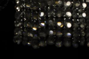 structuur van transparant glas in kunstmatig licht. details van kroonluchter gemaakt van glas in donker. foto