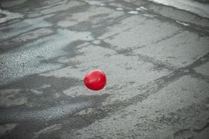 rood bal vliegt over- asfalt. ballon buiten. foto