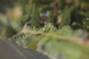 toeristen Gaan bergop in zomer. hiking. speelgoed- figuren van mensen Aan model- van bergachtig Oppervlakte. foto