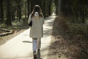 meisje in wit kleren wandelingen door park. vrouw Aan lang loopbrug. foto