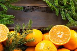 verse mandarijnen in bruine doos op houten achtergrond met groene dennentakken. frame, kopieer ruimte, vakantie en wintergeur, nieuwjaar, kerstmis. gezonde voeding, jus d'orange, etalage. snijden en snijden foto