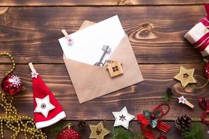 Kerst plat lag op een houten achtergrond met sleutels tot nieuw huis in het midden met een envelop met een notitieblad. nieuwjaar, overdracht, aandelen van de hypotheek, de verhuur van een huisje. ruimte voor tekst foto
