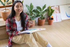 jong meisje zittend Aan de verdieping en schilderij Aan papier Bij huis. hobby en kunst studie Bij huis. foto