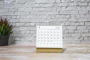 juni 2022 wit kalender met ingemaakt fabriek Aan houten bureau. foto