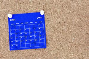 juli 2023 blauw kalender met pin Aan kurk bulletin aanplakbord. foto