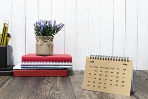 bruin mei kalender 2023 kalender Aan houten bureau met kantoor briefpapier. foto