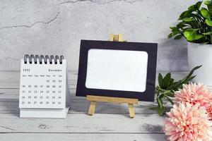 wit december 2022 kalender Aan houten bureau met papier kader en ingemaakt fabriek. foto