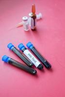 hiv bloed test buis en injectiespuit Aan rood achtergrond foto