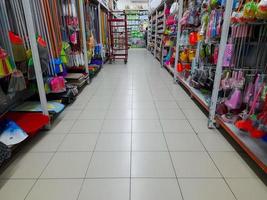 jombang, oosten- Java, Indonesië, 2022 - niemand in een stil winkel gangpad met rijen van schappen gevulde met kleurrijk huishouden items of gereedschap . foto