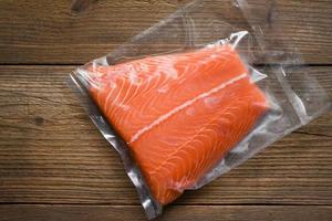 vers rauw Zalm vis steak Aan houten achtergrond -Zalm filet verpakt in plastic vacuüm pak in inpakken verkopen in supermarkt foto