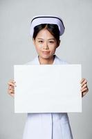 de jonge Aziatische verpleegster toont leeg teken foto