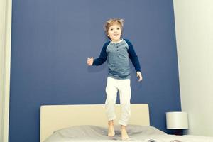 speels kind jumping Aan de bed. foto