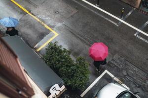 persoon die rode paraplu gebruikt die een straat kruist foto